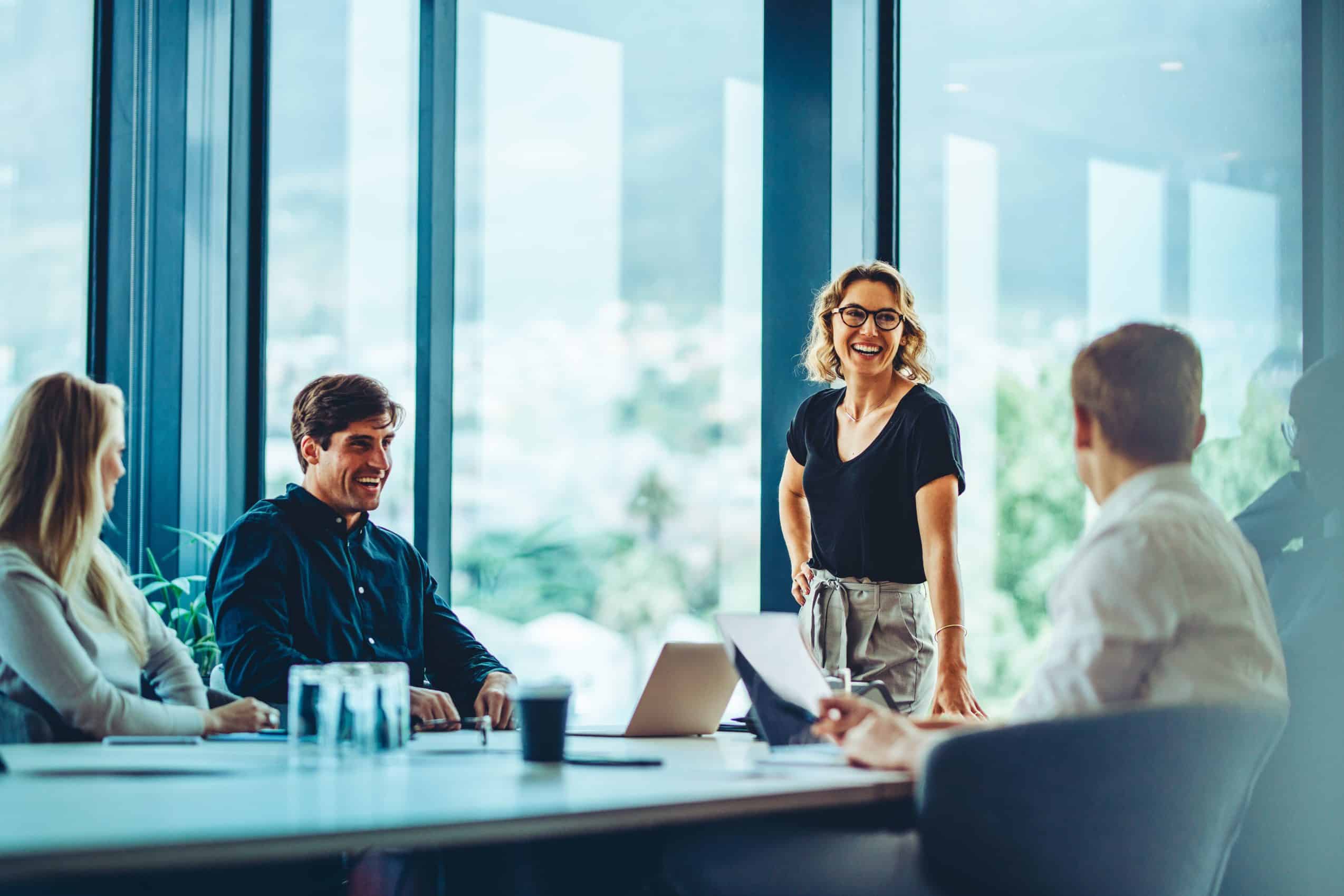 Office colleagues having casual discussion during meeting in conference room. Group of men and women sitting in conference room and smiling.